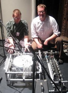 Composers Troy Rogers and Steven Kemper at NIME 2009 with robotic musical instruments PAM (Poly-tangent Automatic (multi-)Monochord) and MADI (Multi-mallet Automatic Drumming Instrument). These musical robots were designed and built by Expressive Machines Musical Instruments (EMMI).