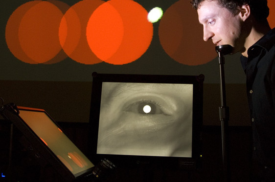 Anthony Hornof performs EyeMusic, a musical and multimedia work composed by Troy Rogers with Hornof and Tim Halverson, in which eye movements are sensed with the aid of an eye tracker and mapped to audio and visual control parameters. Photo credit: Anthony Hornof