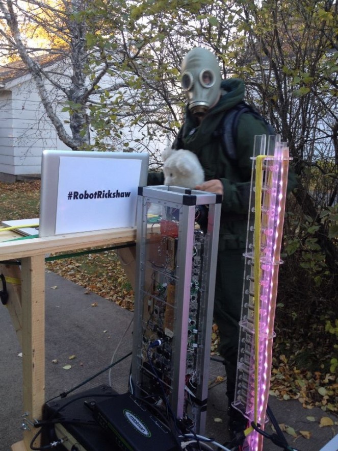 Robot Rickshaw, a cart full of robotic musical instruments piloted by a lunatic in a hazmat suit+teddy bear, prepares to embark upon a walk in Duluth, MN. Photo credit: Melissa Maki